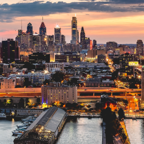 Panoramic photo of the Philly skyline at dusk featuring the Delaware River and bridge