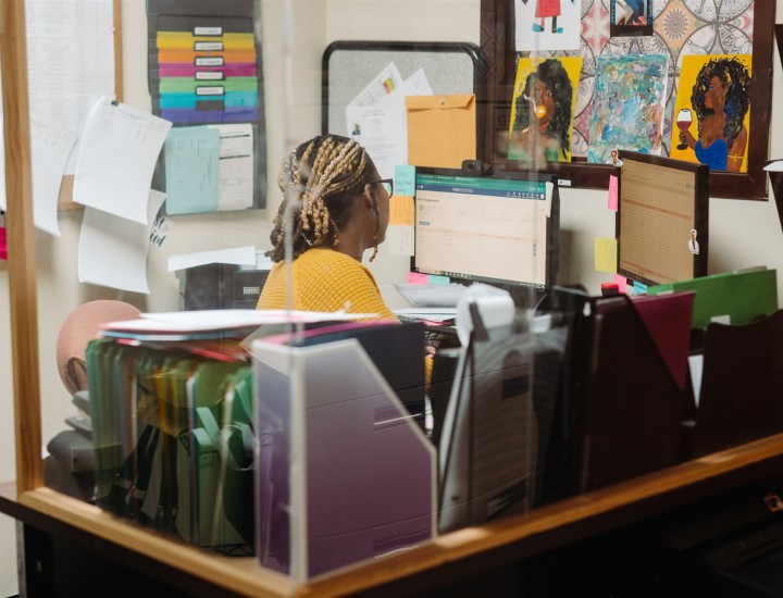 Employee sitting at her desk looking at her computer with back to the camera 