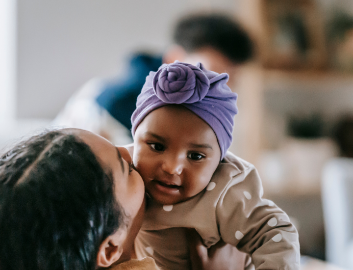 mother kissing baby daughter on cheek